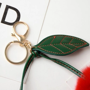 Detail of red faux fur cherry keychain with green PU leaves and gold metal ring