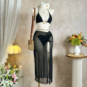 Three-piece black bikini set with mesh cover-up skirt, gold ring detail and beach accessories