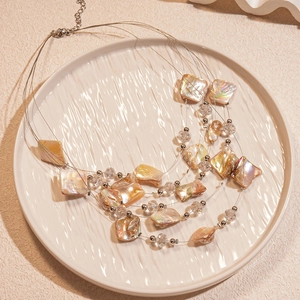 Detail view of multi-layer shell necklace with iridescent beads and lobster clasp