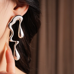 Gros plan d'une boucle d'oreille en forme de goutte d'argent irrégulière sur un modèle