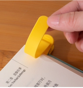Detailed view of yellow silicone hands-free auto-follow bookmark clipped on a book page