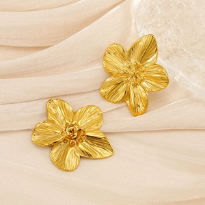 Detailed macro view of golden five-petal flower stud earrings with brushed texture finish