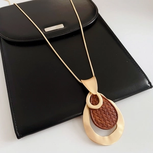 Close-up of golden teardrop pendant with woven texture leather on sleek snake chain