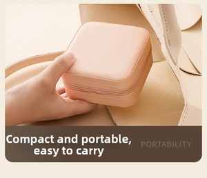 Mini pink PU leather jewelry box being placed in a handbag for portable travel storage