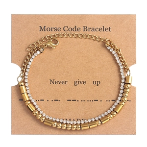 Close-up of golden Morse code double-layer bracelet with rhinestones on display card