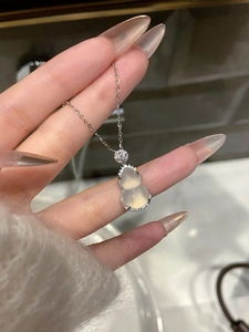 Close-up of a stainless steel gourd pendant necklace with white opal and zircon details