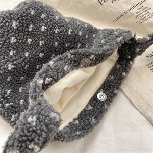 Détail de sac seau en peluche grise avec fermoir magnétique et texture en polaire douce