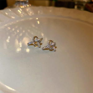 Macro shot of silver knot stud earrings with cubic zirconia on a white ceramic plate