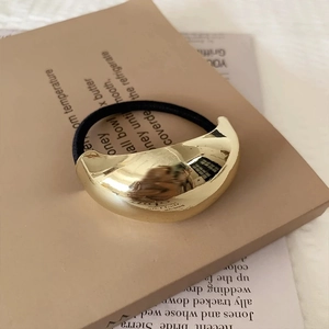 Detailed view of a sleek golden metallic hair ring on high-elastic black cord