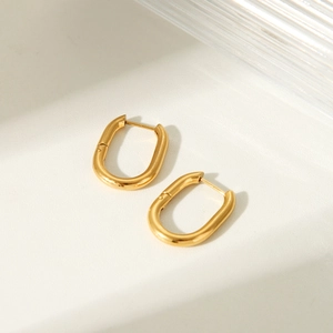 Minimalist gold plated stainless steel U-shaped hoop earrings on a textured surface