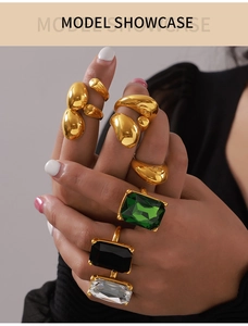 Close-up of gold geometric rings with emerald and crystal gemstones on hand
