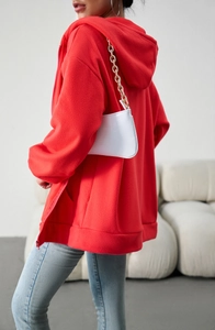 Detail of red oversized hooded zip-up sweatshirt with soft fleece texture and relaxed fit