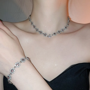 Close-up of floral necklace and bracelet set with pink crystals and silver finish