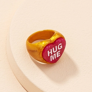 Macro shot of pink and amber resin heart ring with white Hug Me engraving text
