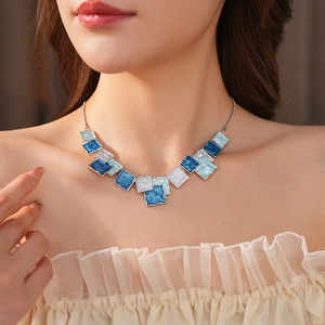Close-up of blue and white enamel square pendant necklace on a female model neck