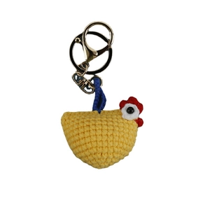 Handmade yellow crochet chicken keychain with red comb and blue cord on white background