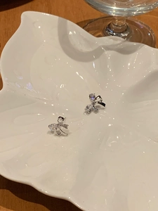 Macro shot of silver bow stud earrings with sparkling zircons on a decorative ceramic tray