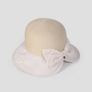 Detail of elegant straw sun hat with large fabric bow and textured weave contrast
