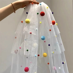 Detail of white multi-layered mesh veil with colorful plush pompoms for party photography