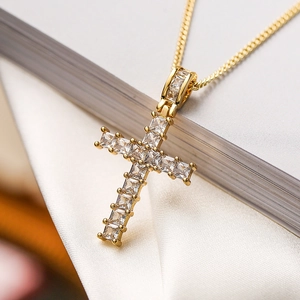 Macro detail of gold-plated cross pendant with shimmering square-cut zircon stones
