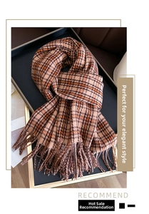 Detail of warm brown plaid scarf with long fringe on a black display tray