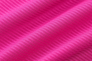 Détail macro du tissu en maille côtelée magenta montrant sa texture douce et fluide