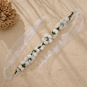 Detail of white floral headband with realistic flowers and green leaves on beige background