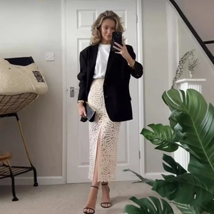 Ensemble élégant avec blazer noir, haut blanc et jupe midi en dentelle beige