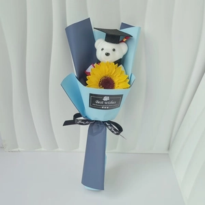 Detail of graduation teddy bear and yellow sunflower bouquet with Best Wishes message
