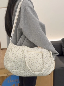 Vista dettagliata della borsa da viaggio trapuntata a fiori sulla spalla della modella