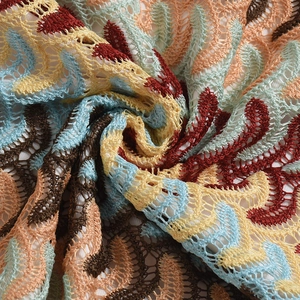 Vue macro détaillée d'une broderie colorée ondulée sur un tissu en dentelle ajourée