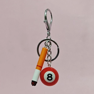 Mini cigarette and billiard ball keychain with silver metal rings on pink background