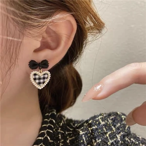 Detail of velvet bow earring with black and white checkered heart and faux pearl trim