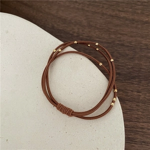 Detail of triple-layer brown elastic hair ties with decorative gold metallic beads