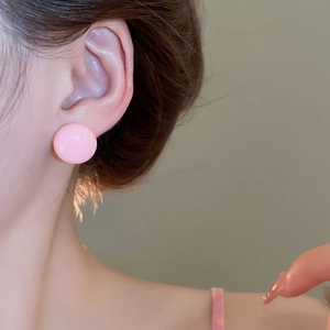 Close-up of a pink semi-sphere stud earring worn on ear with soft matte finish