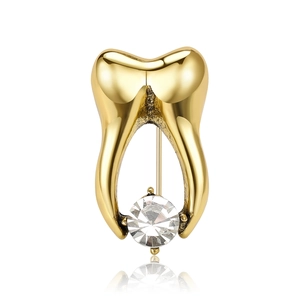 Vintage gold tooth brooch with clear rhinestone accent on a clean white background