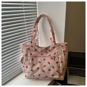 Detailed view of pink corduroy tote bag with strawberry print and zipper front pocket