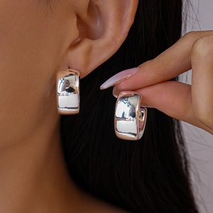 Close-up of thick silver circle hoop earrings with polished mirror finish on model