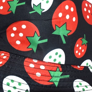 Close-up of strawberry print fabric on black bucket hat with neat stitched brim detail