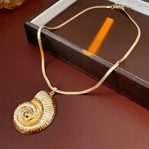 Detail of a golden seashell pendant necklace on a sleek flat snake chain in a gift box