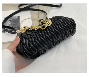 Close-up of black pleated PU leather shell bag with chunky gold chain and metal handle