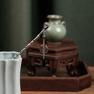 Detailed view of silver branch hair stick with black bead tassel in ceramic vase