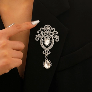 Baroque crystal brooch with teardrop pendant worn on a black blazer lapel detail