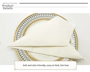 Detailed close-up of white embossed napkins with textured scroll patterns on a gold-rimmed plate
