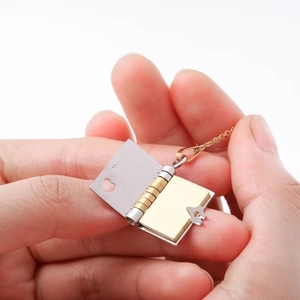 Macro view of bicolour stainless steel book locket with heart cutout and key clasp