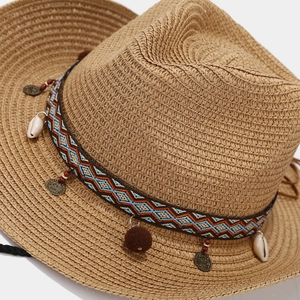 Close-up of straw beach hat with ethnic blue band, seashells, and bronze coins
