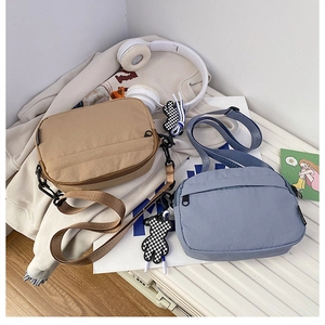 Détail de sacs bandoulière en nylon macaron en kaki et bleu avec breloques d'ours