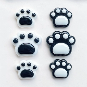 Macro view of assorted black and white resin cat paw charms for DIY phone case making