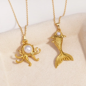 Gros plan de pendentifs océan en plaqué or avec poulpe, poisson et perles blanches