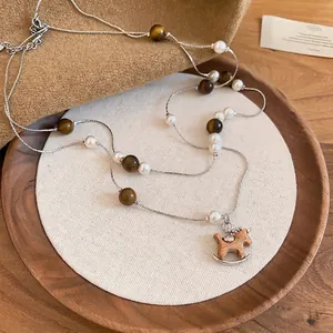 Collier en oeil de tigre et perles avec pendentif cheval de bois sur présentoir lin